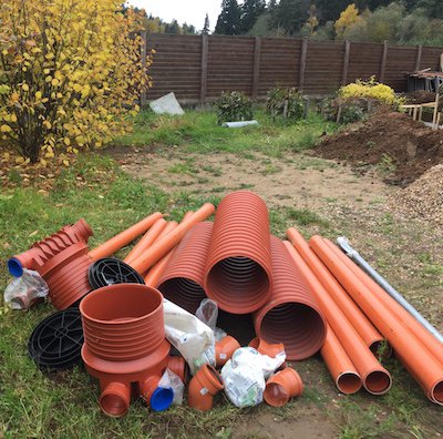 Пластиковые инспекционные колодцы 315мм Uponor и канализационные трубы, на газоне перед началом монтажных работ.